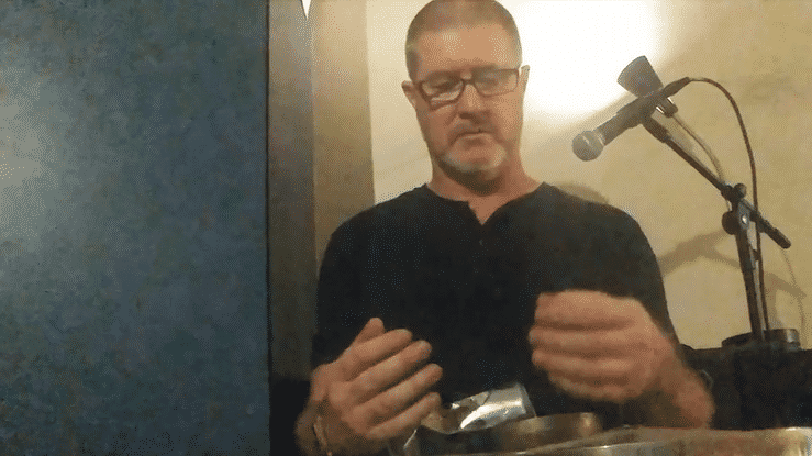 a gif of Kristian attempting to pick up a bowl with hands that are frozen to movement