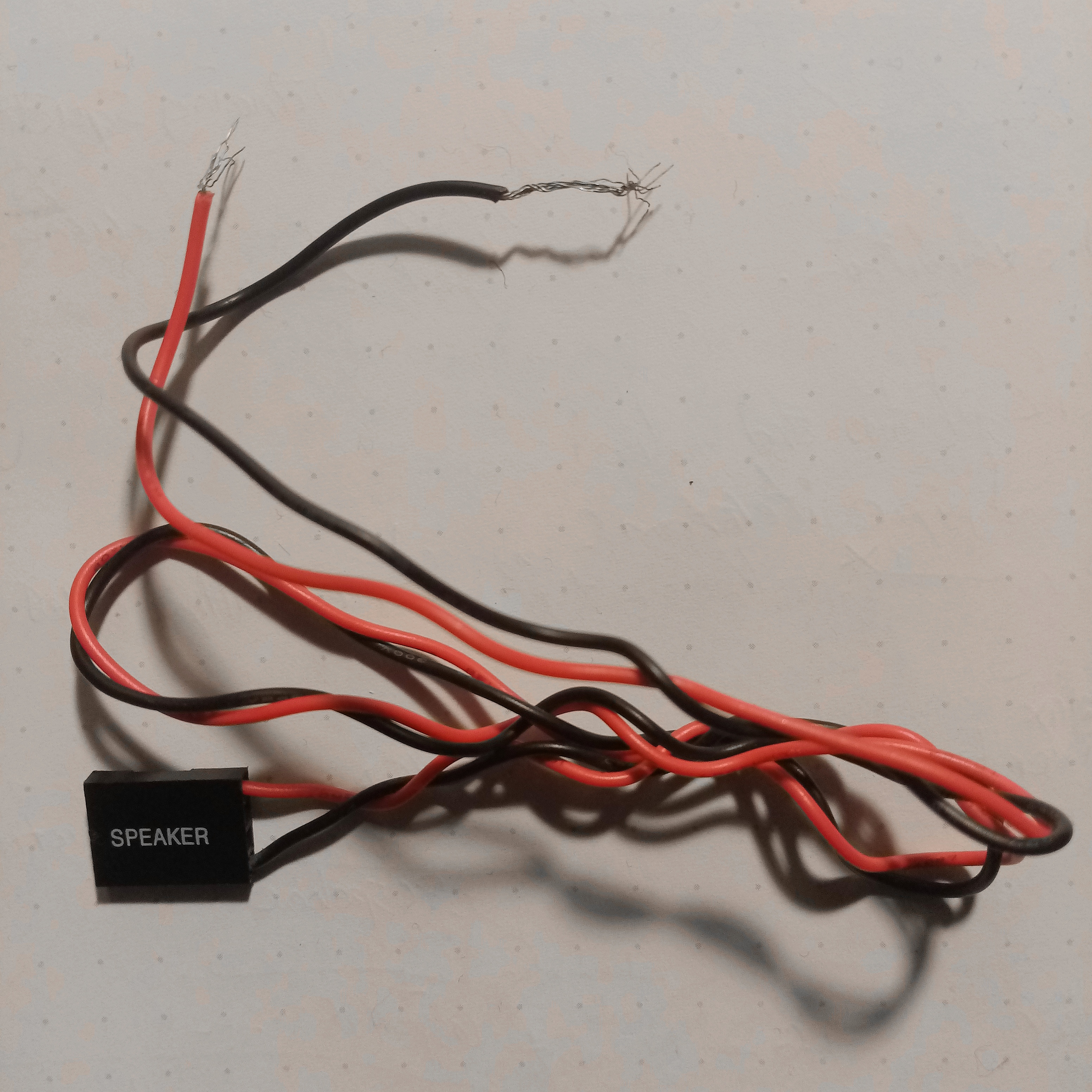 Twisted and frayed red and black electrical wire going into a chip labeled 'speaker'