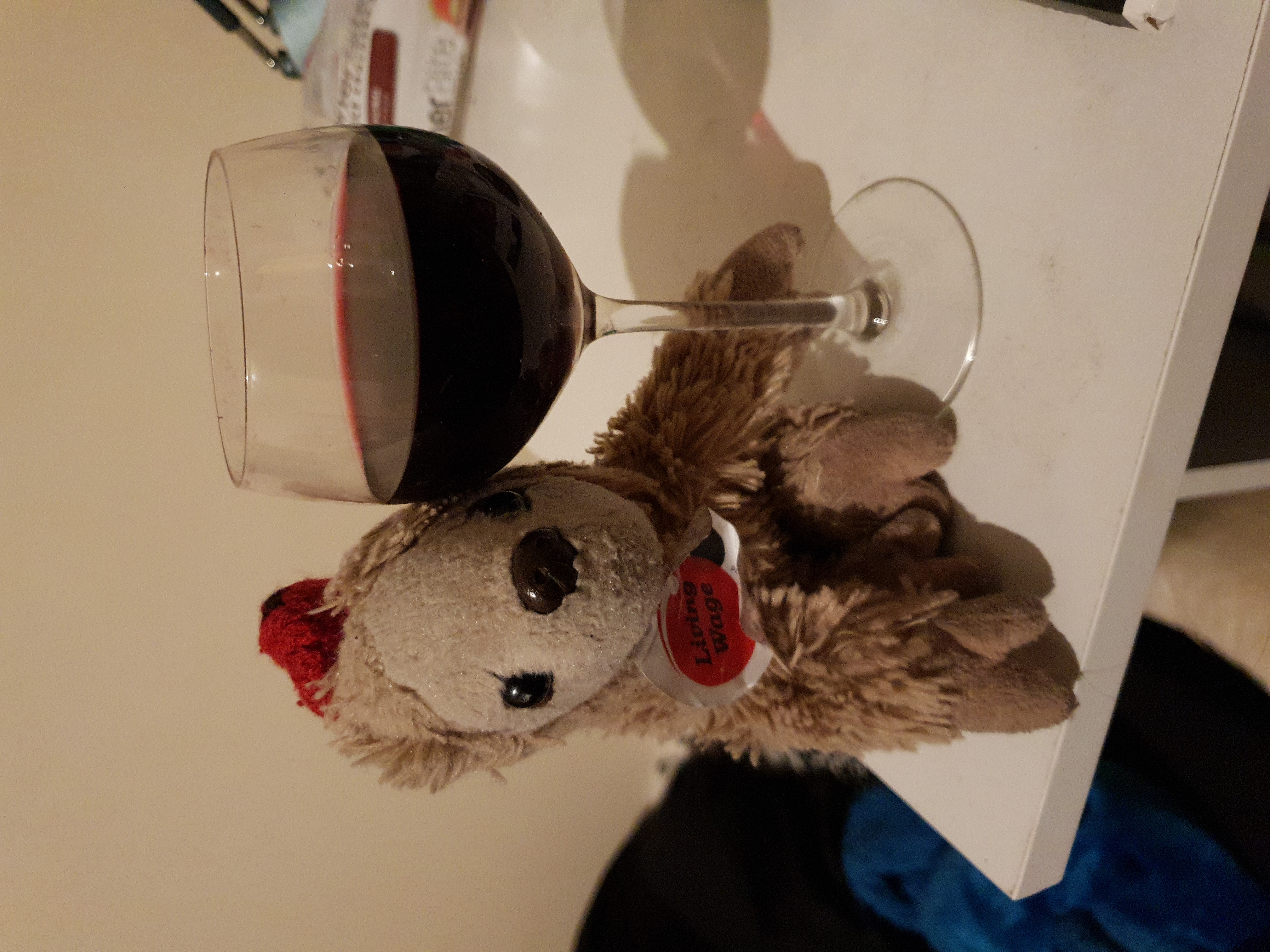 Comrade snuggleton, a soft toy sloth, with a large glass of red wine