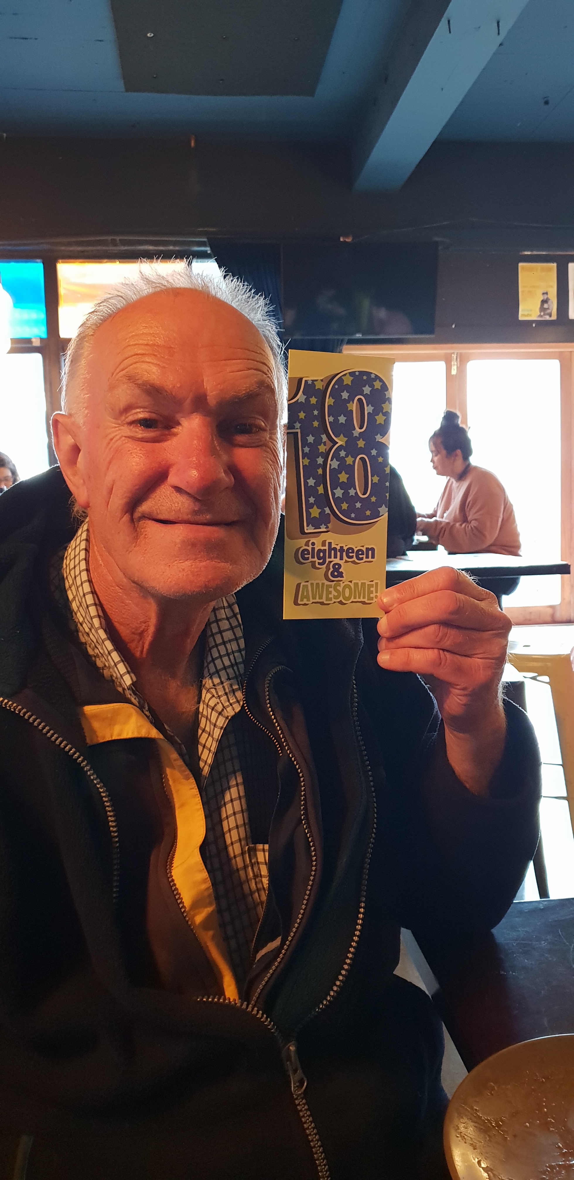 Gerry, an older man, holding a card that reads 18 and awesome