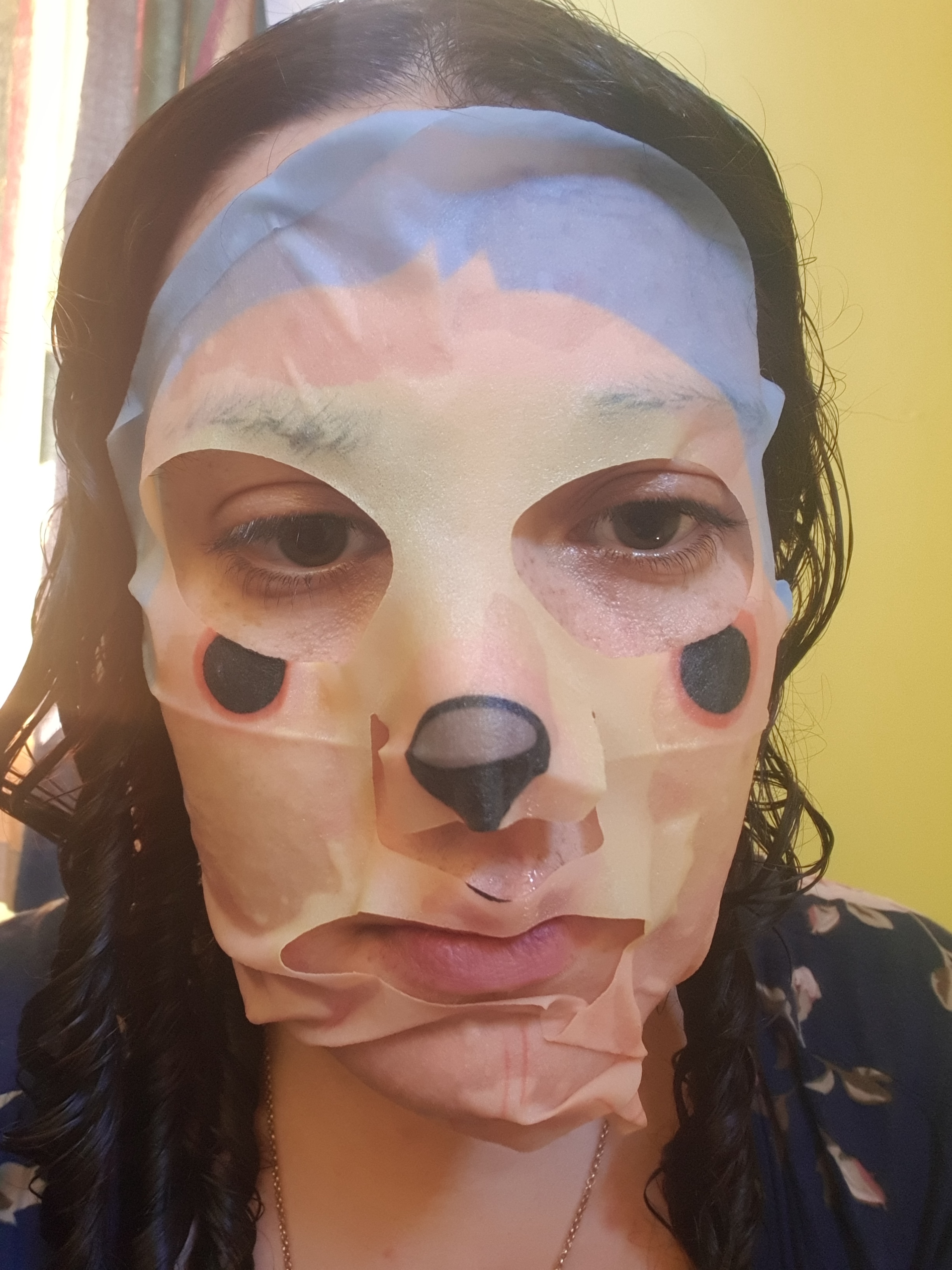 Marika in a thin face mask for skin care, it has a sloths nose printed on it.