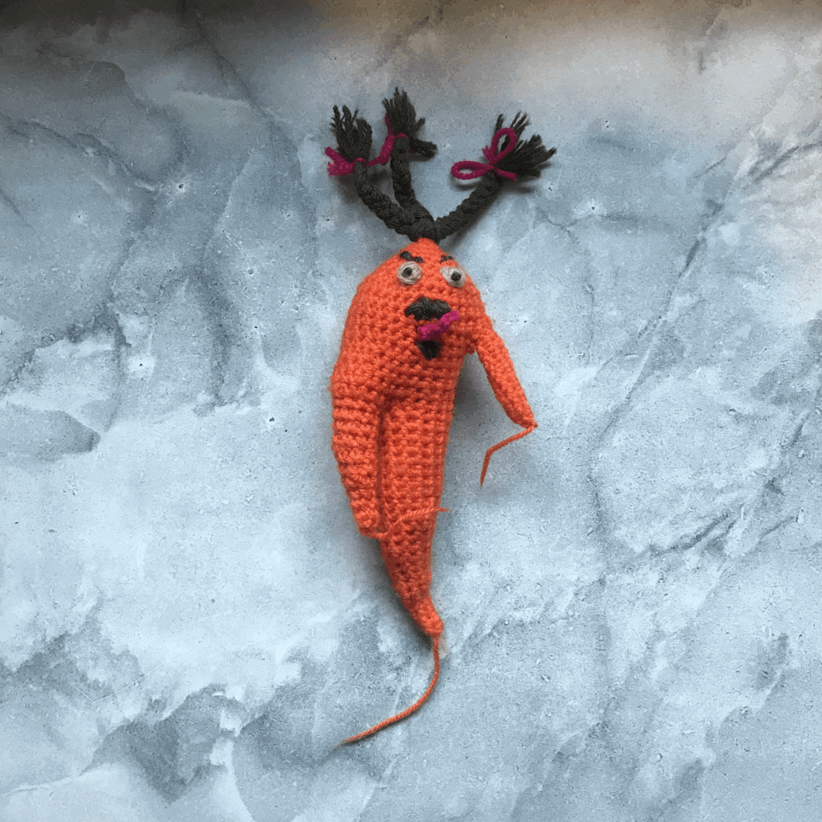 a crochet carrot looks angry. It spins around and around. It pauses and we zoom into its face. Its tongue is red and poking out.