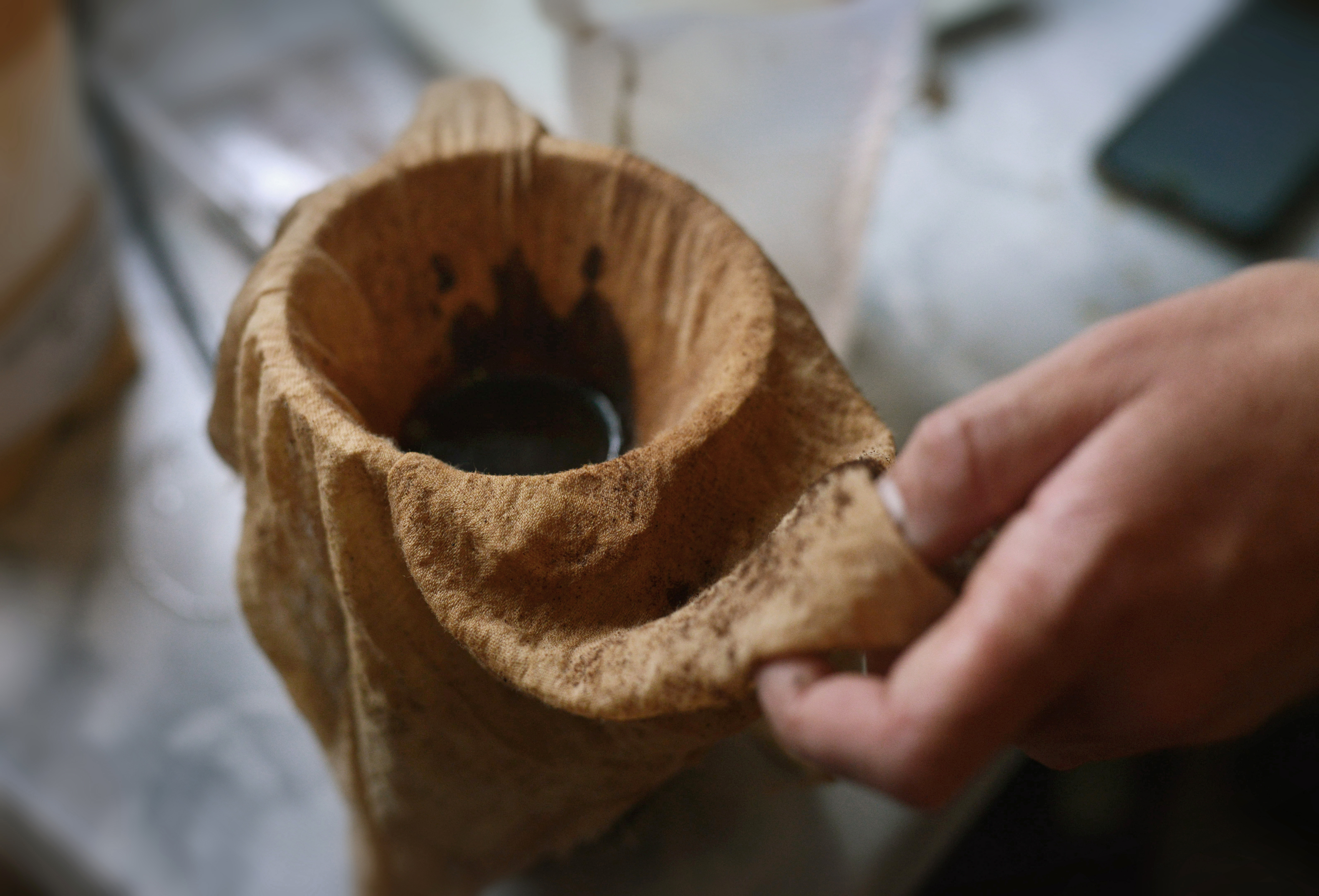 coffee grounds being strained through a stained cheesecloth