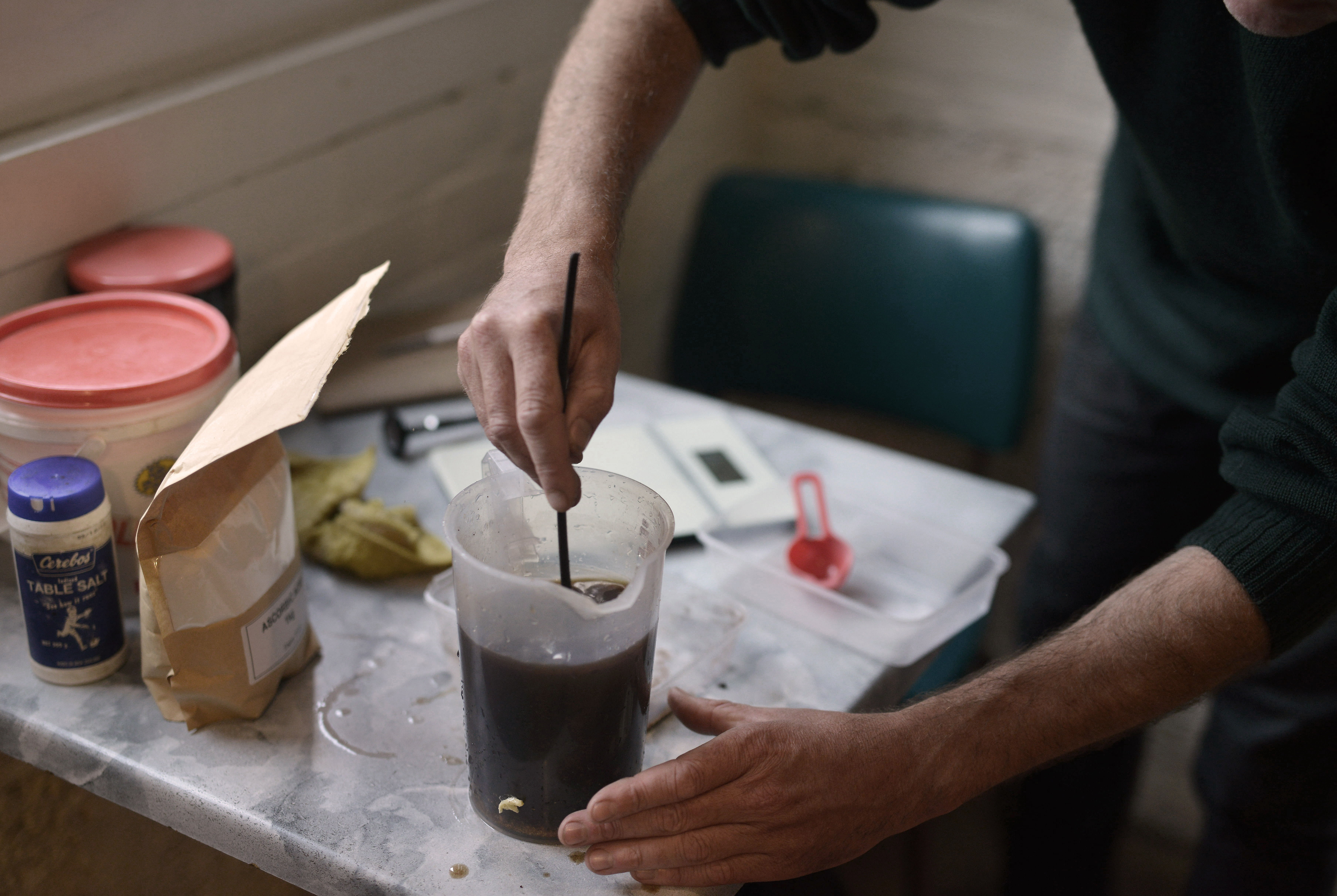 a person stirring a brown liquid in a plastic jug