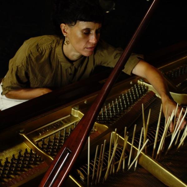 Hermione reaching into the innards of a grand piano. There are chopsticks thrust between the strings and standing upright.