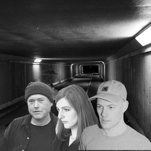A black and white photo of the pedestrian tunnel under Wellington Airport. Collaged on top are the head and shoulders of Amy, Cory, and Omit.
