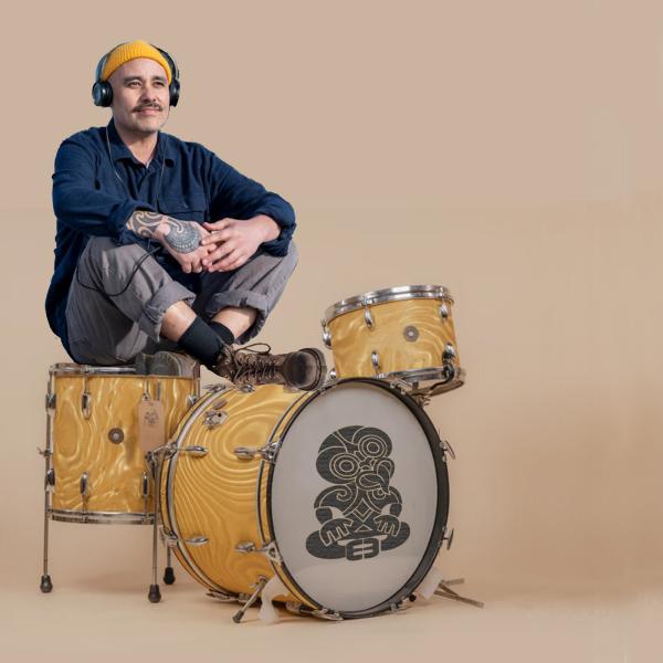Riki sits on drum kit