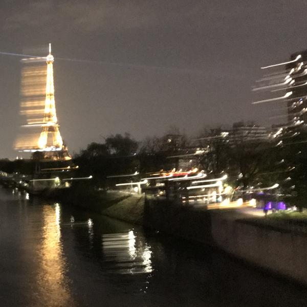 a highly blurred  photo of the Paris. The lights of the Eiffel Tower blurred with rapid movement of the camera.