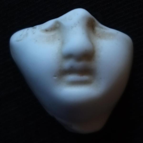 A broken shard of the bottom half of a porcelain doll's face