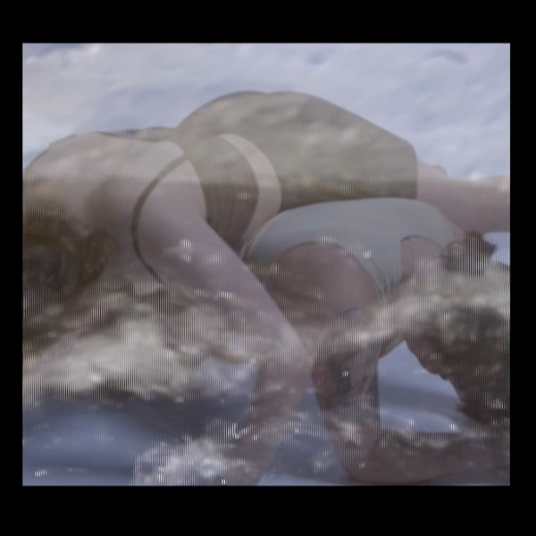 A still from the video work. Two bodies lay over each other cross ways and face down. The bottom person is up on their elbows making for a 'bridge' shape. The image os slightly blurred with a transparent layer that appears to be a churning sea.