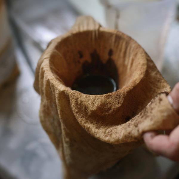 coffee grounds being strained through a stained cheesecloth