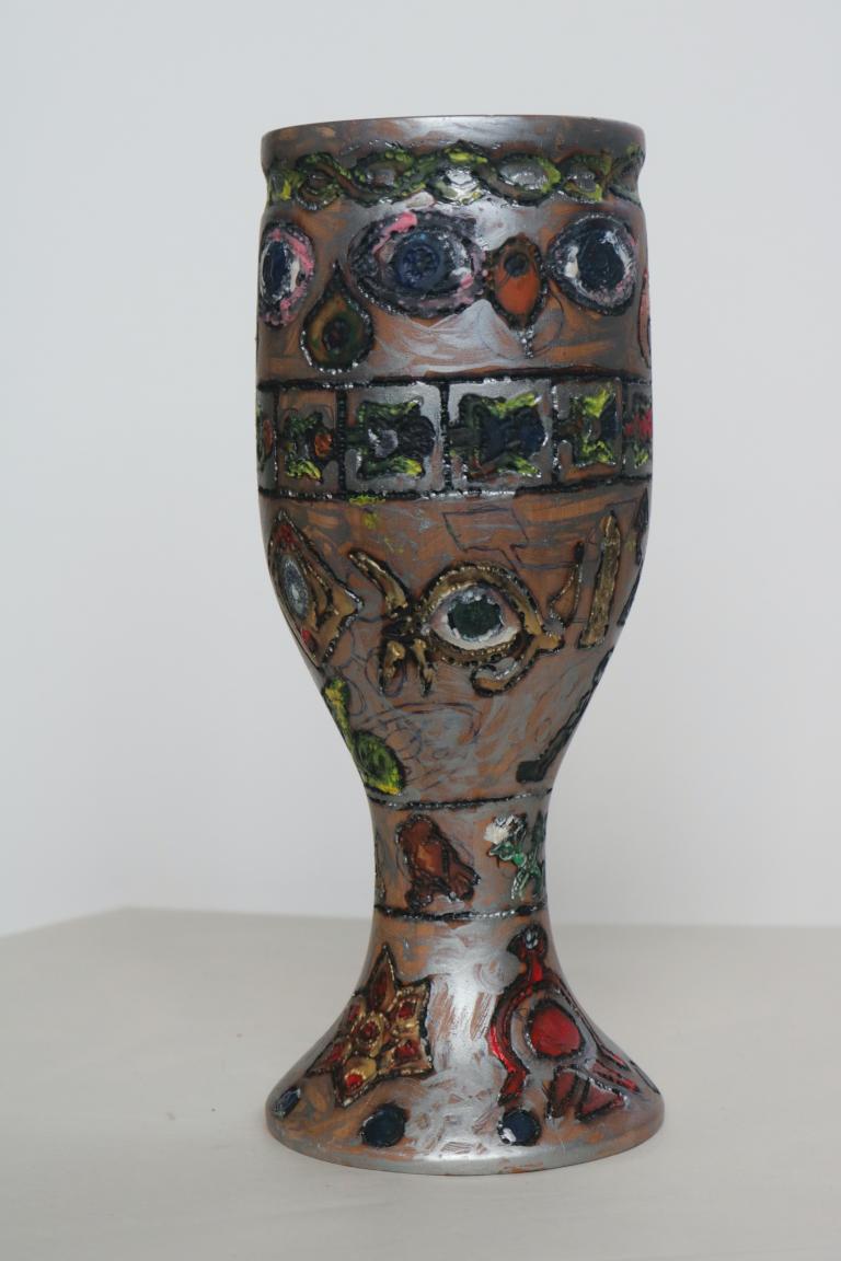 a chalice of wood. painted silver and decorated with shapes similar to eyes