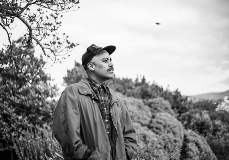 a black and whit portrait of Riki looking our over a block of bush.