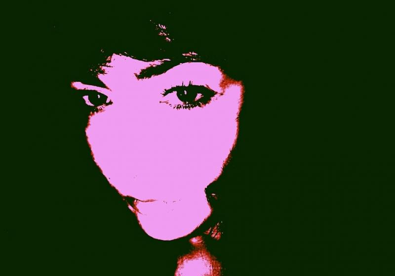 A high contrast portrait. Emilie is pink. The effect is pop art. Her hair is as black as the surroundings.