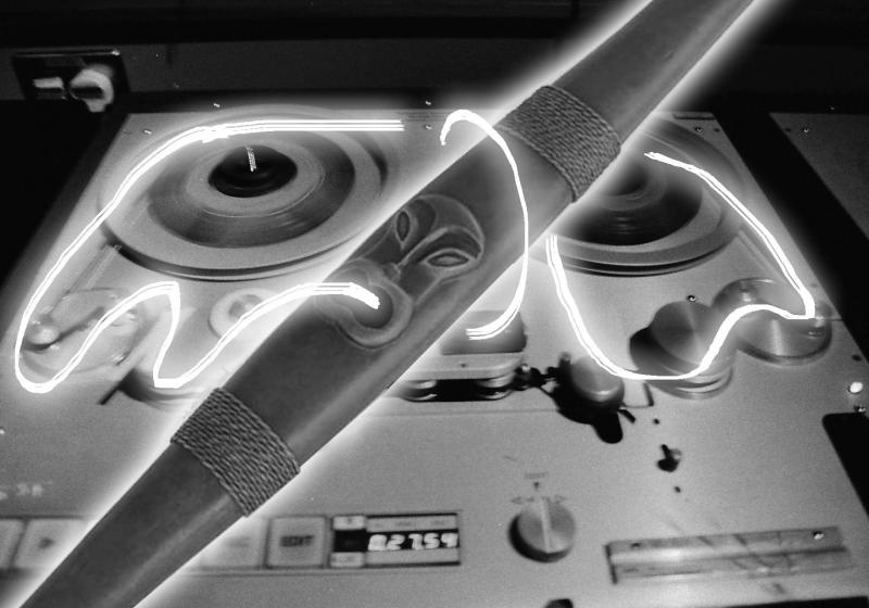 a pūtōrino is aglow, white neon magnetic tape cascading around it and fusing it to a reel to reel
