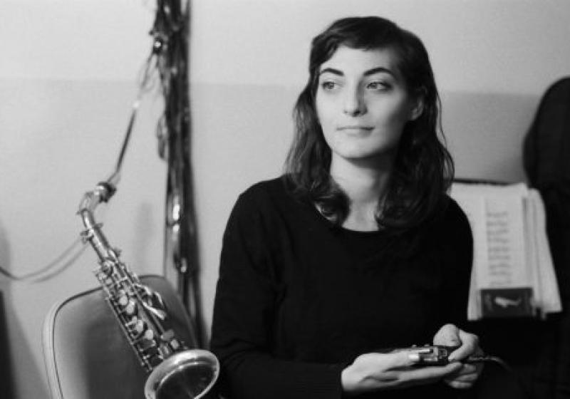 Lea Bertucci lounges on a chair with her saxophone behind her