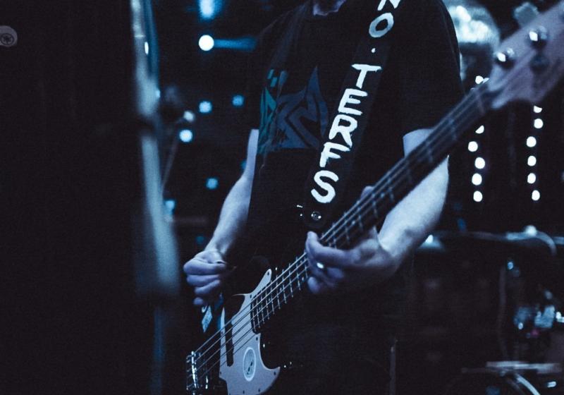Ru Hunter playing a guitar on a dimly lit blue stage