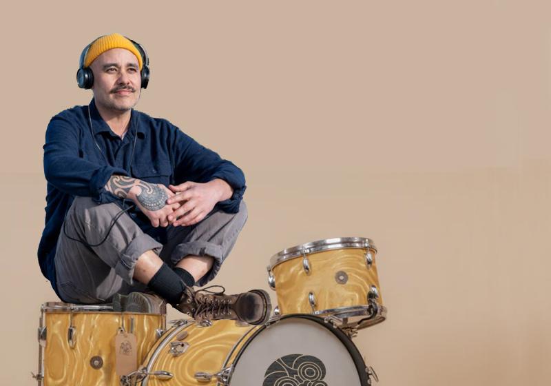 Riki sits on drum kit
