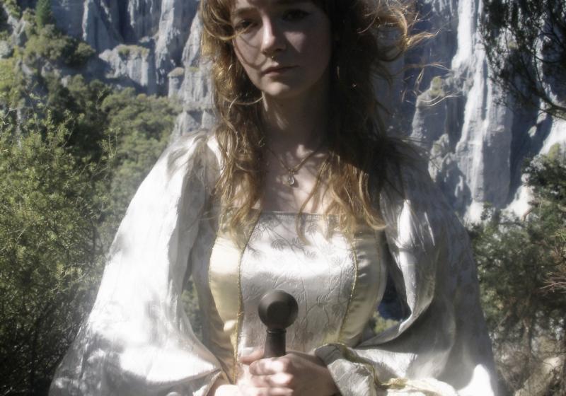 A mystical photograph of Fox Moss at Putangirua Pinnacles, staring at the camera with a sword in her hands