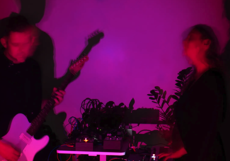 a pink-washed photo of Apertures performing live