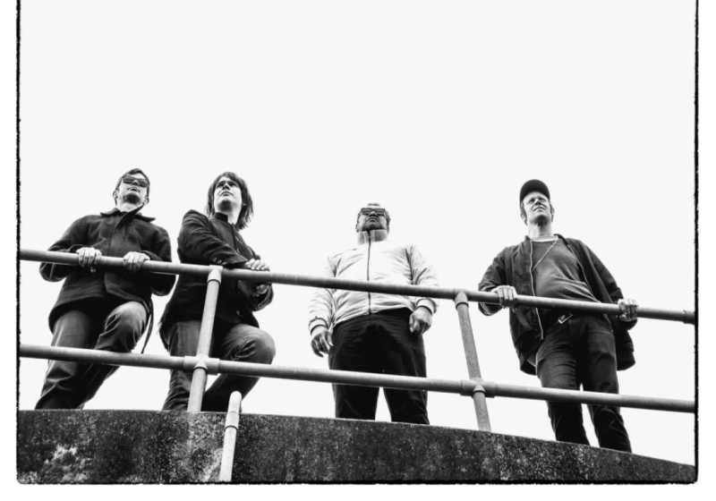 Black and white photo of a band on a balcony looking out happily into the distance