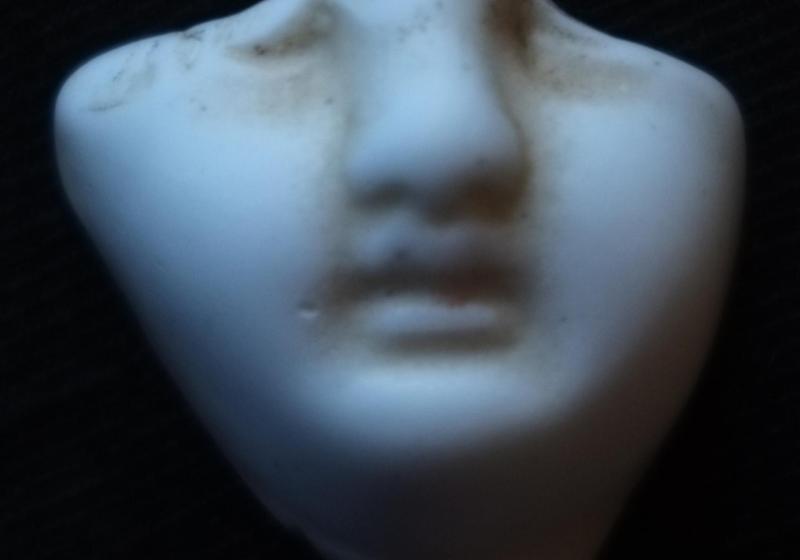 A broken shard of the bottom half of a porcelain doll's face