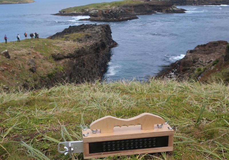 A photo of a homemade wooden analogue video camera, on a hill on a subantarctic islands, looking over the ocean