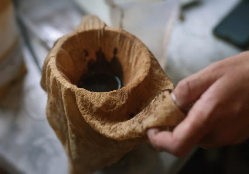 coffee grounds being strained through a stained cheesecloth