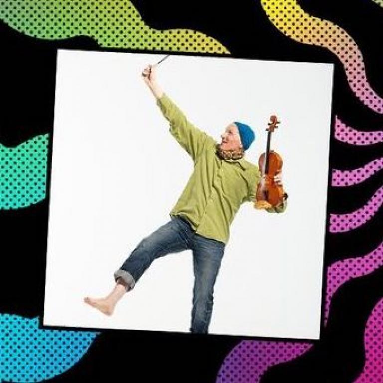 Chris looking wacky. Holding a violin and raising a hand to the air.