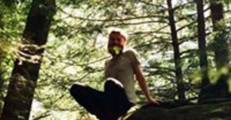 a pixelated photo of a person sitting on a forest floor