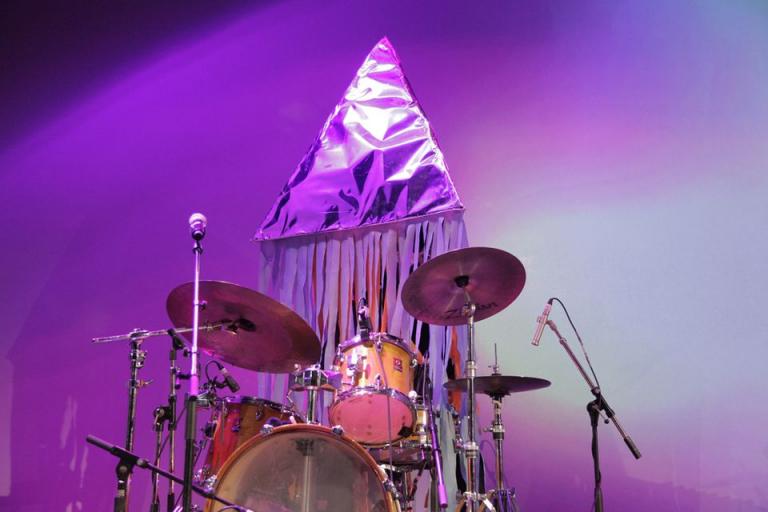 Andrew playing drums. There is no wasy of knowing it is him as he is wearing a huge silver pyramid over his head. It has paper tassels cascading down hiding his torso.