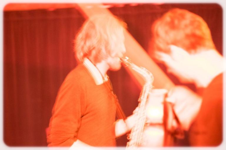 a blurry sepia toned photo of Glen with his saxophone