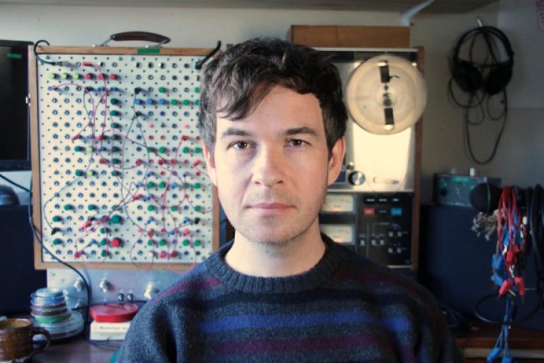 A young Kraus stands in front of his home made modular synthesiser.