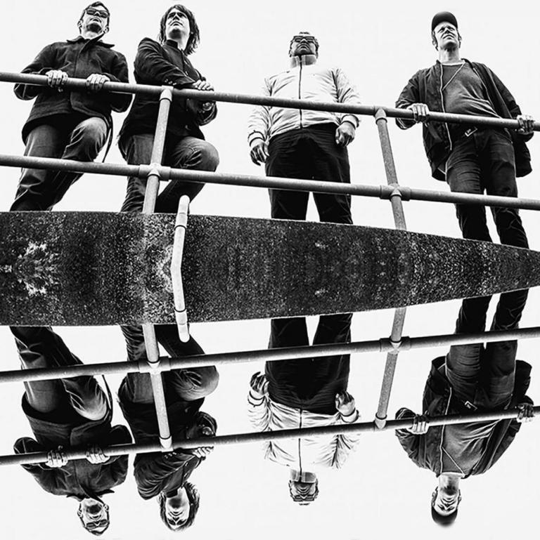 A photo of the band standing by a long metal hand rail