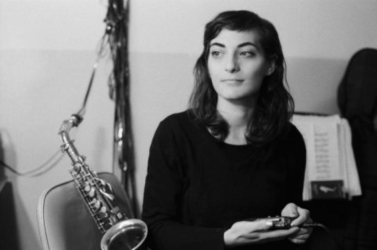 Lea Bertucci lounges on a chair with her saxophone behind her