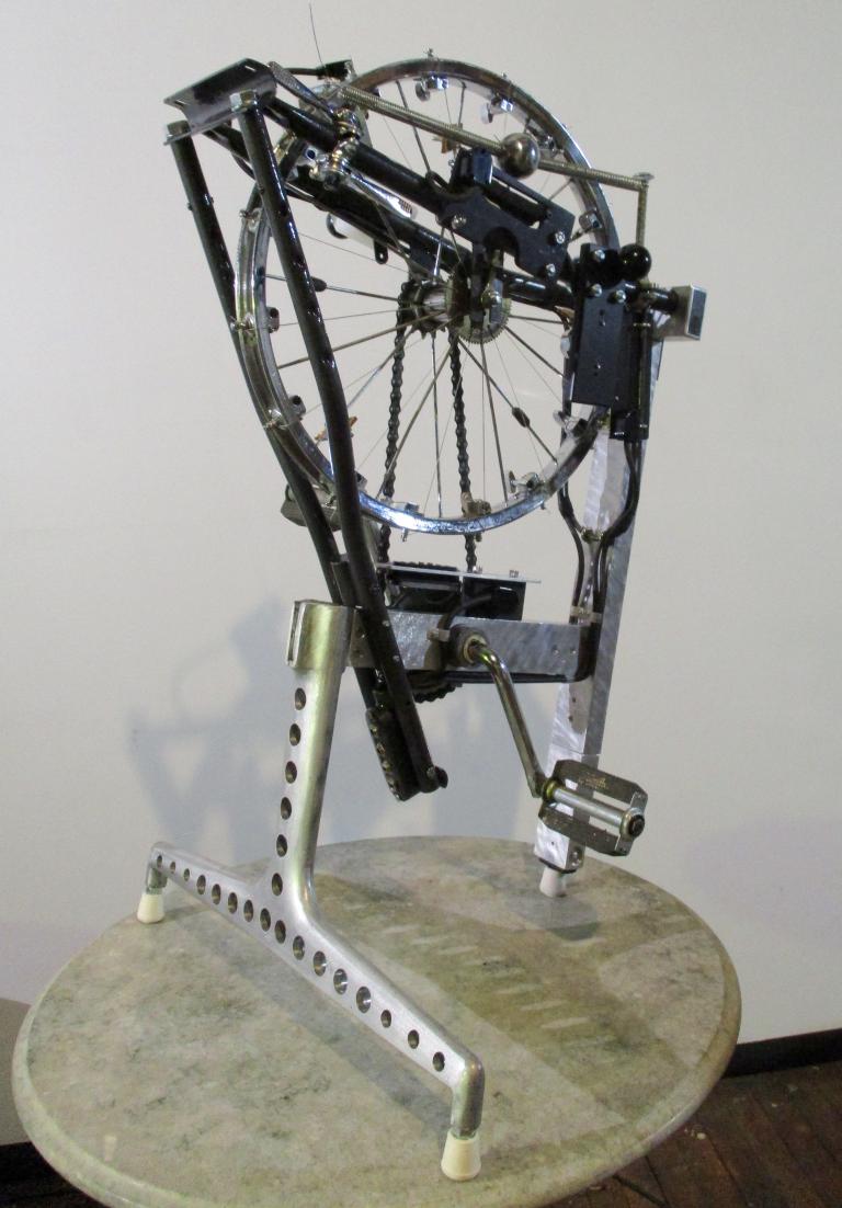 Neil Feather's 'Melocycle' invented instrument from 2016. The instrument combines a bicycle wheel with pedals and some kind of mechanism that appears to perhaps strum the spokes of the wheel. 