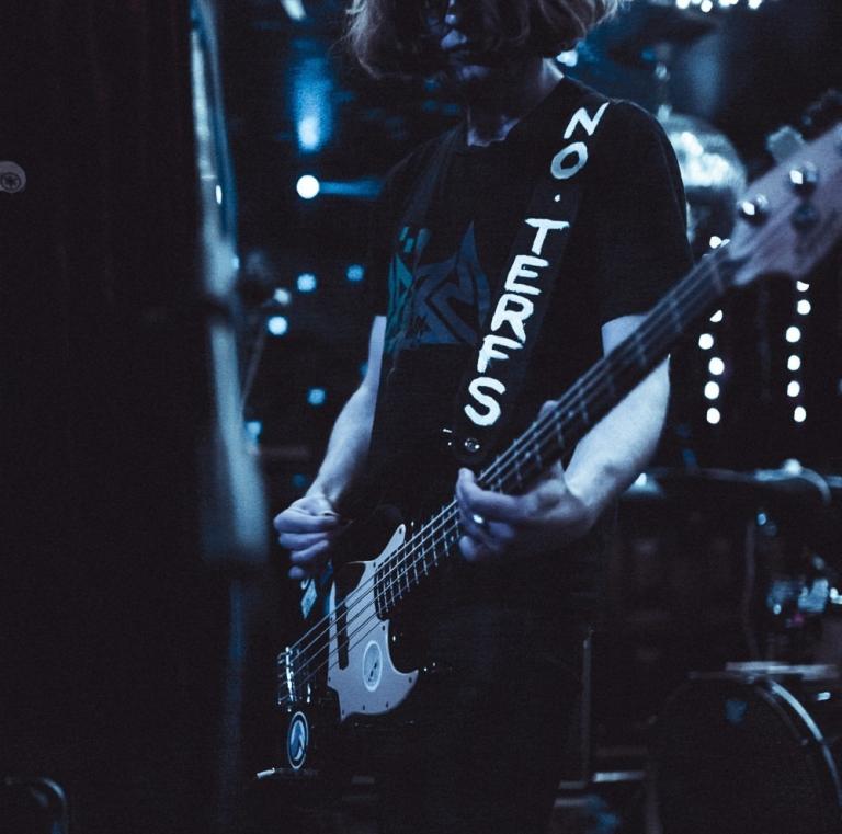 Ru Hunter playing a guitar on a dimly lit blue stage