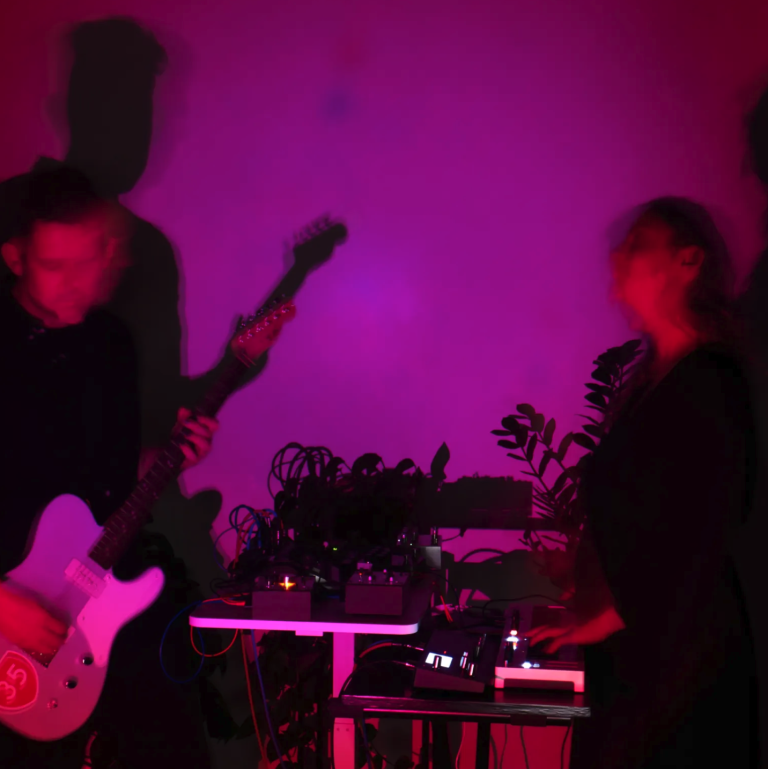a pink-washed photo of Apertures performing live