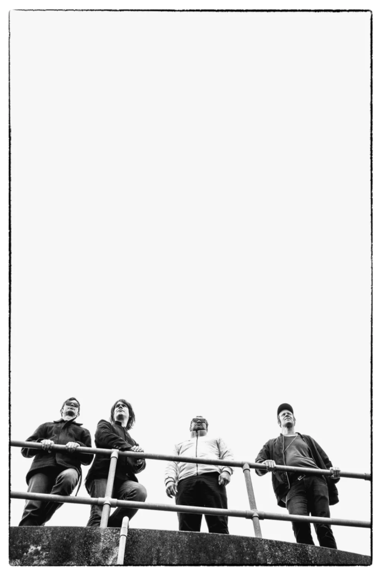 Black and white photo of a band on a balcony looking out happily into the distance