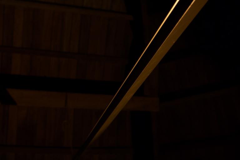 a very dark shot of a metal beam. The bacjground is so dark the beam could be in space, but there are just enough hints of wood in the distance to know it is in the dome of the observatory