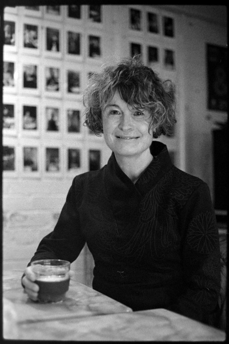 a seated person holding a glass of coffee and smiling
